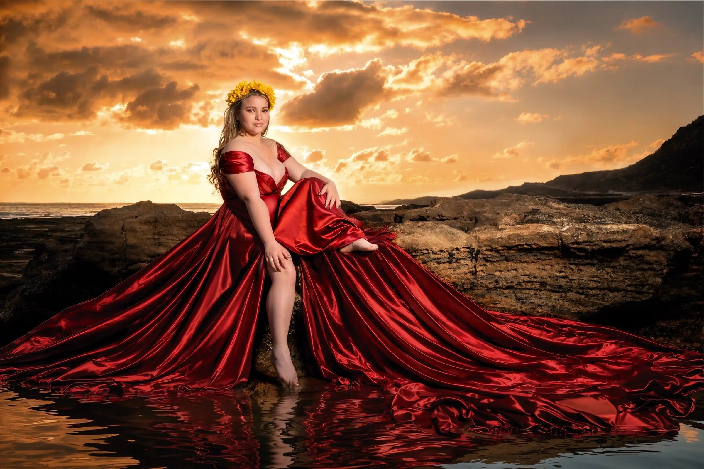 Quinceañera con vestido rojo extendido sobre las rocas al atardecer.