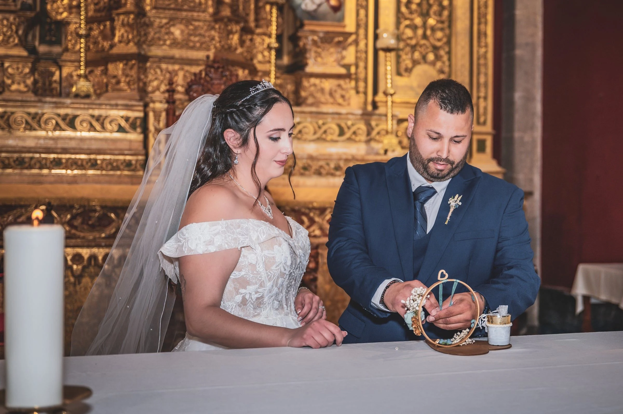 Novios mirando sus manos durante el intercambio de anillos ante el altar.