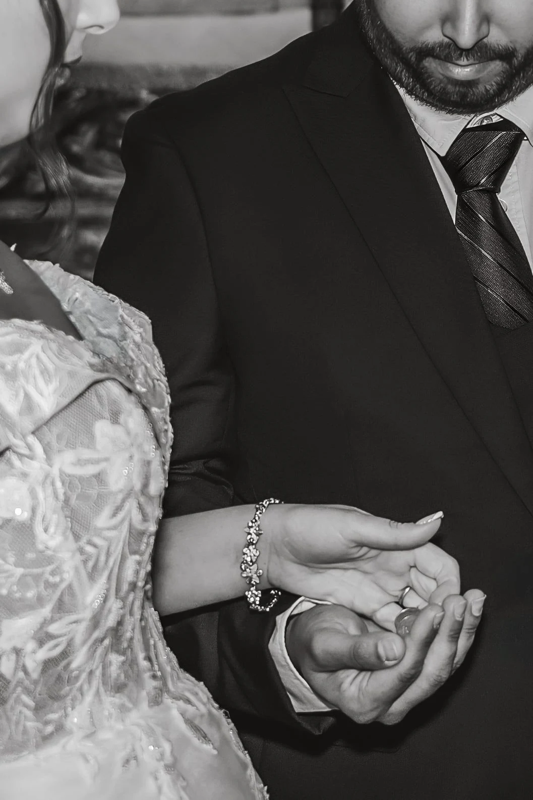 Primer plano en blanco y negro de las manos de los novios durante la ceremonia.