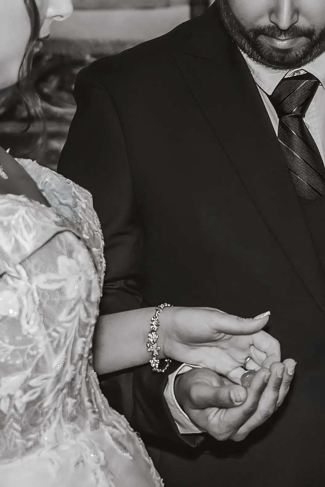 Primer plano en blanco y negro de las manos de los novios durante la ceremonia.