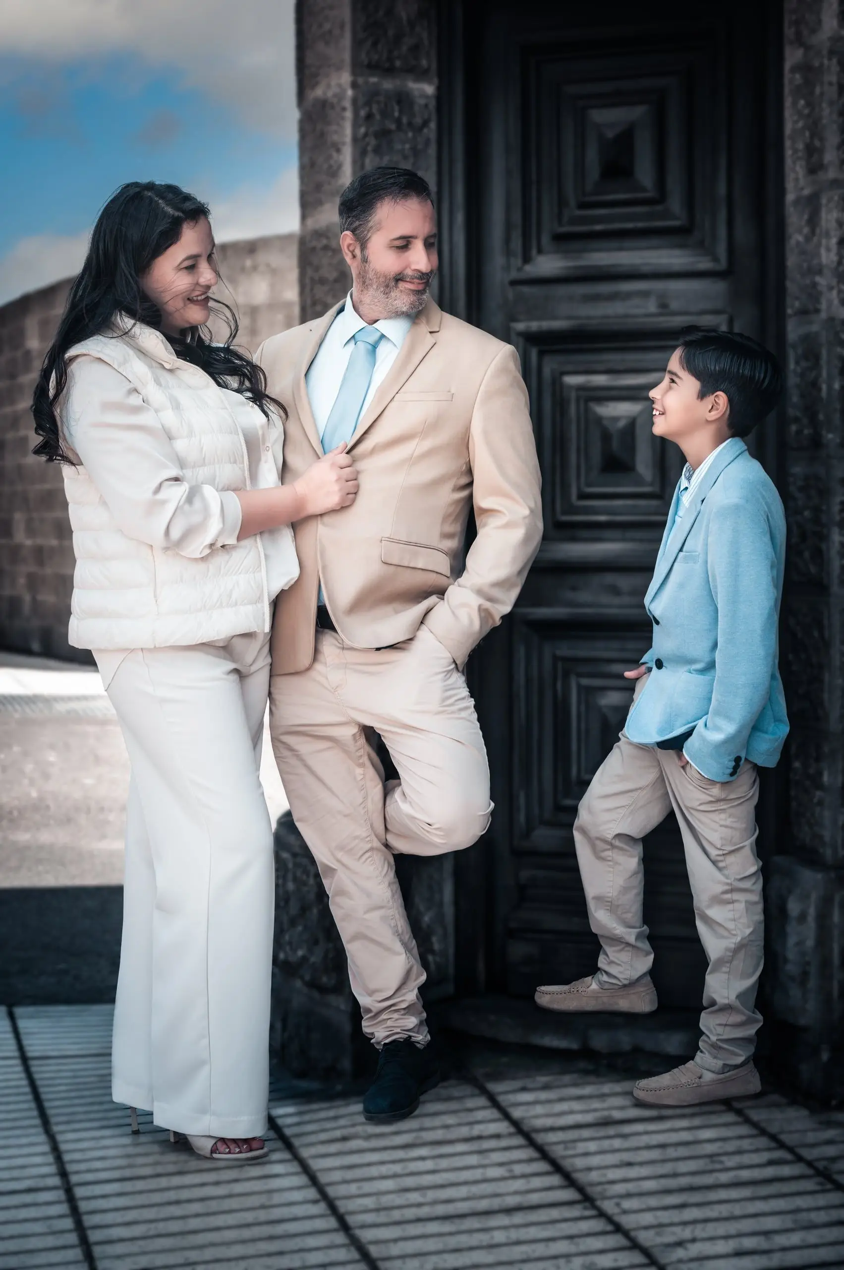 Niño de comunión conversando con sus padres frente a una puerta histórica.