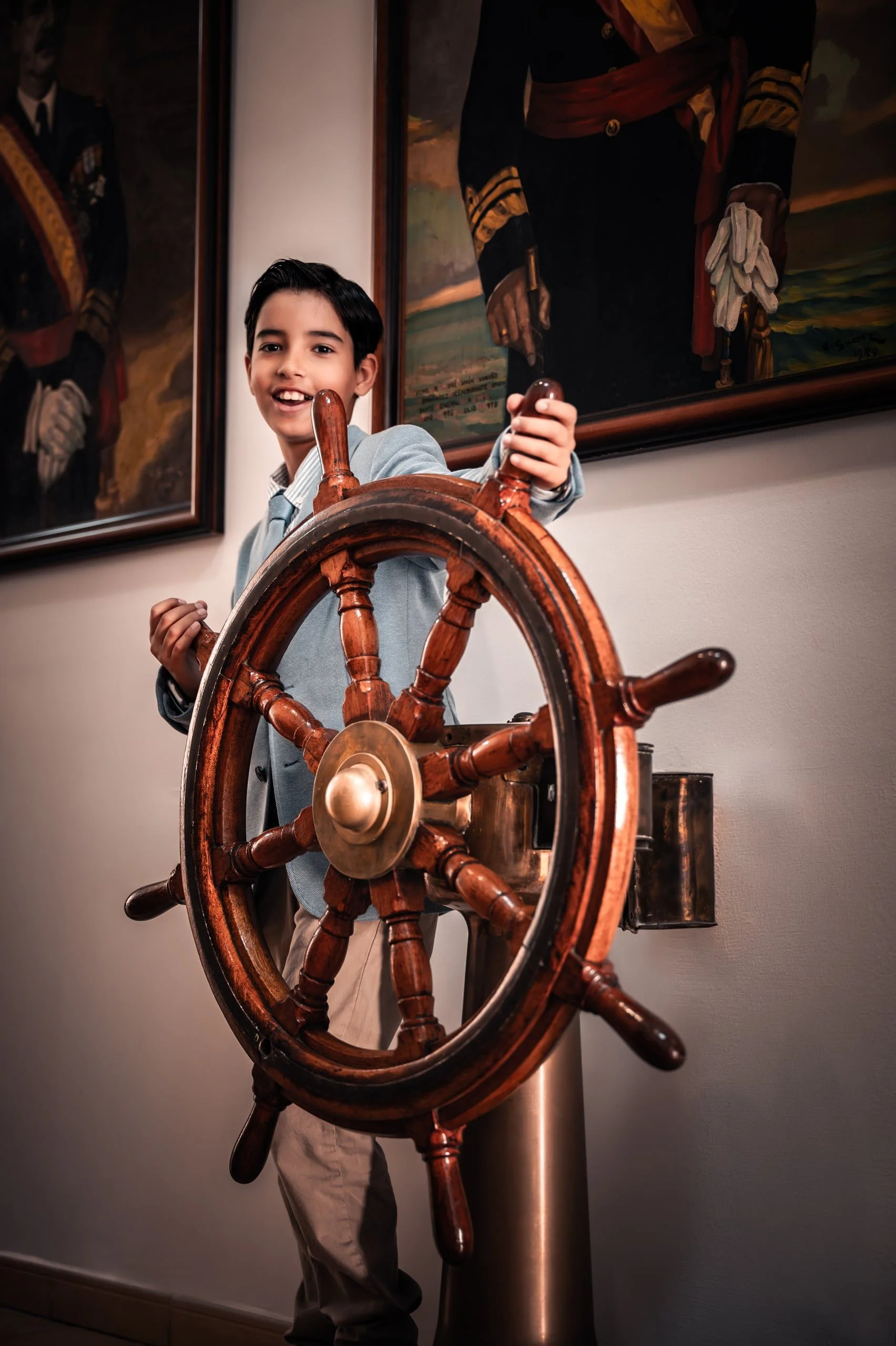Niño sonriente junto al timón de un barco durante su sesión de comunión en Gran Canaria.