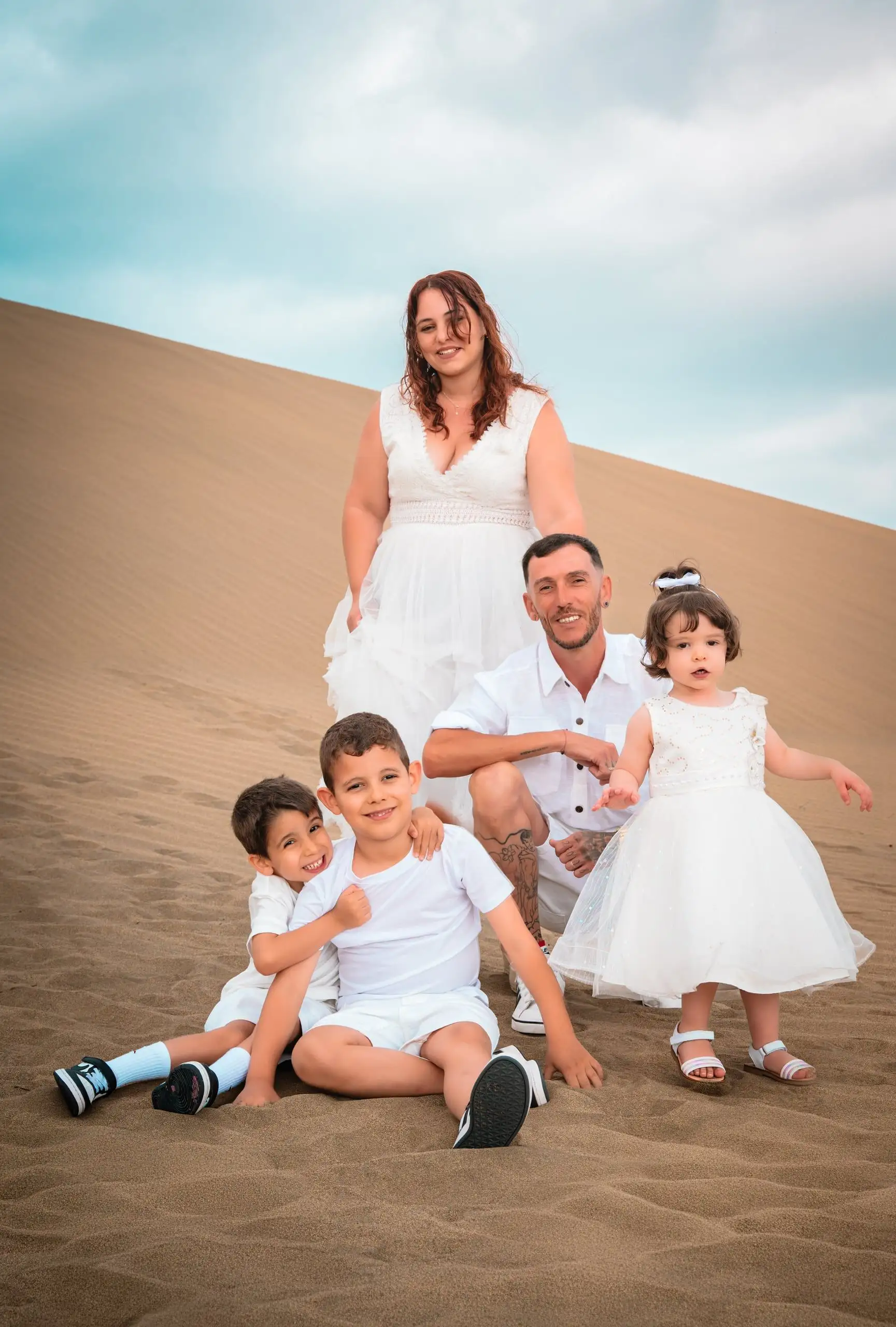 Familia de cinco personas reunida en las dunas durante una sesión al atardecer.