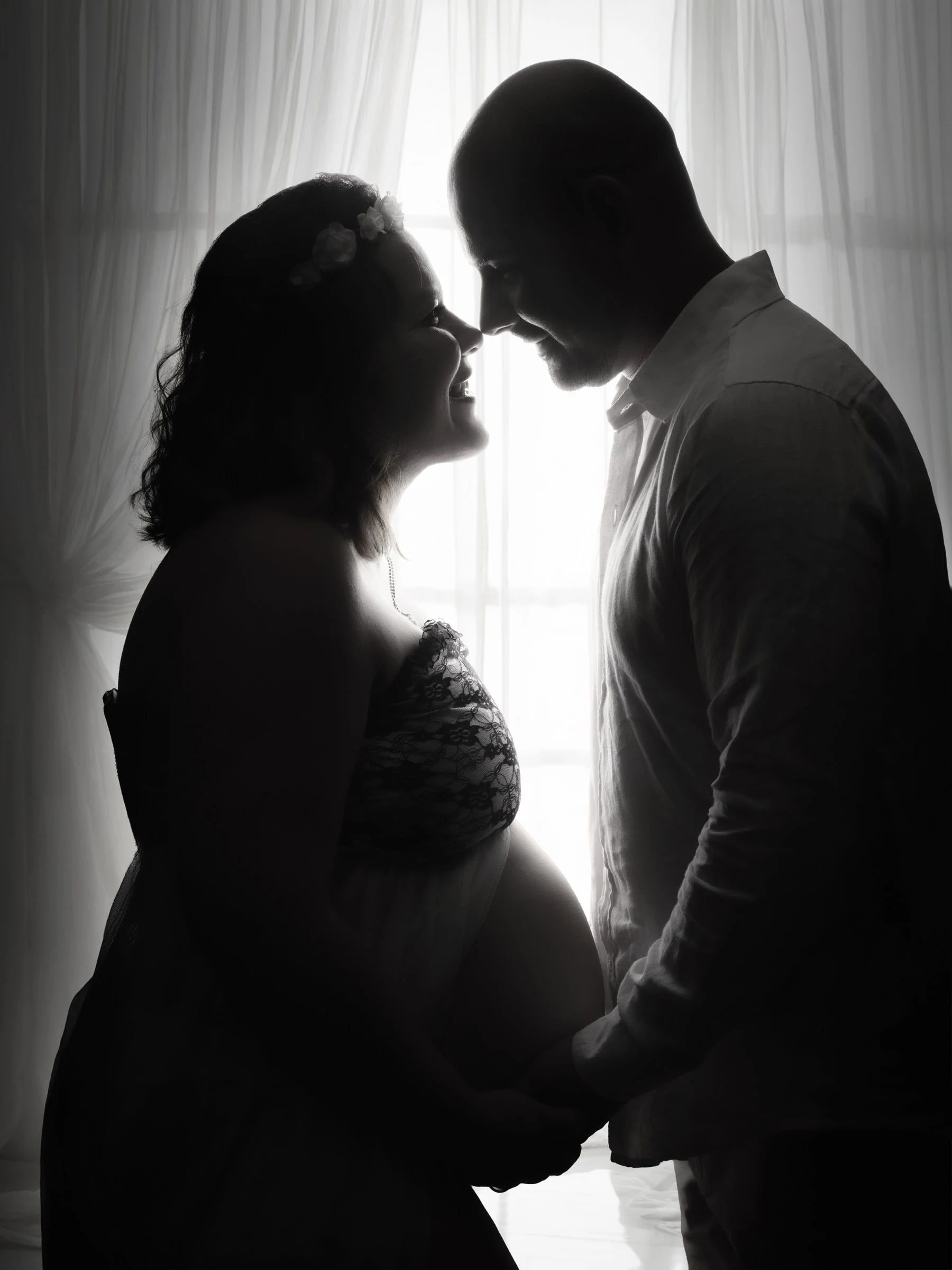 Siluetas de una pareja frente a frente junto a una ventana, en blanco y negro.