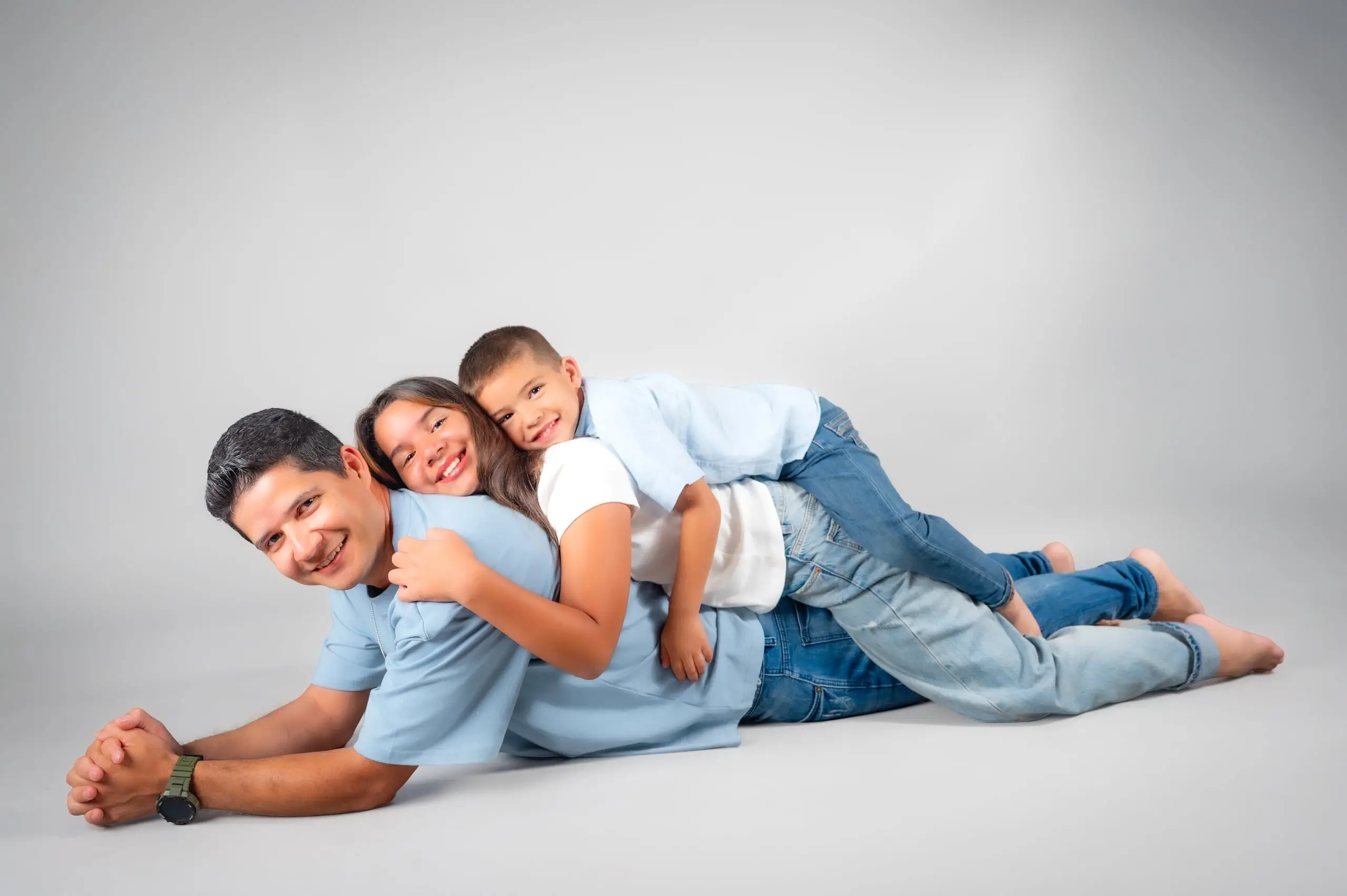 Familia tumbada y abrazada durante una sesión relajada en el estudio.