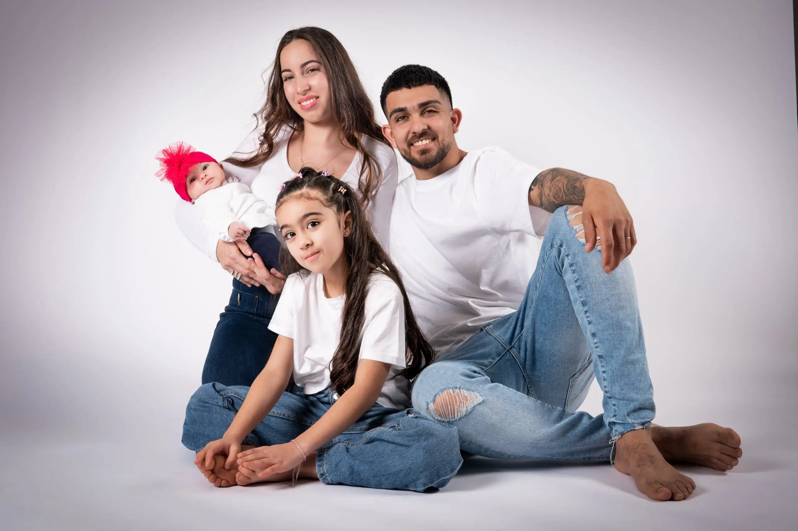 Padres, hija y bebé posan juntos en un retrato de estudio.
