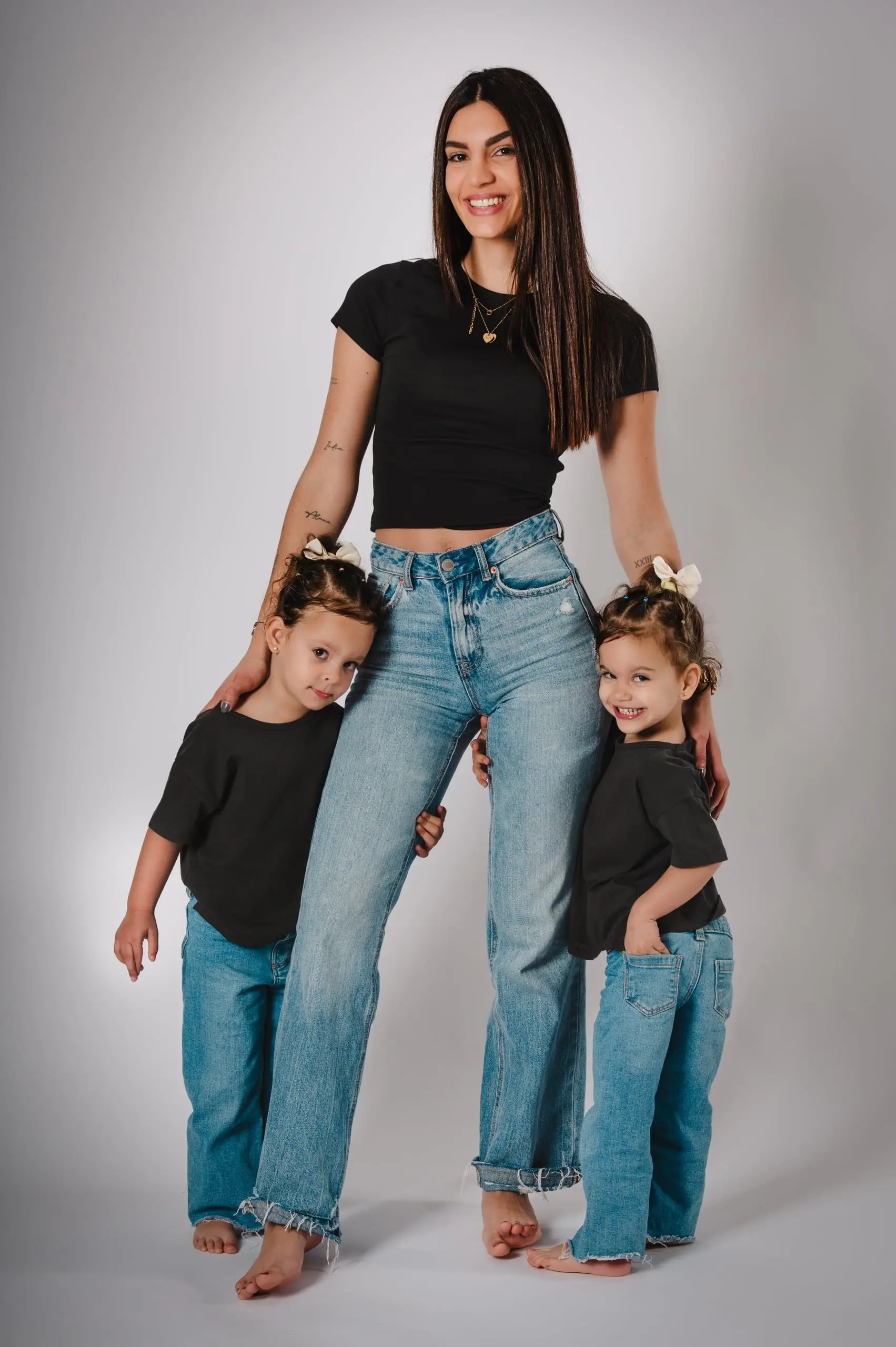 Madre con sus dos hijos pequeños en un retrato de estudio.