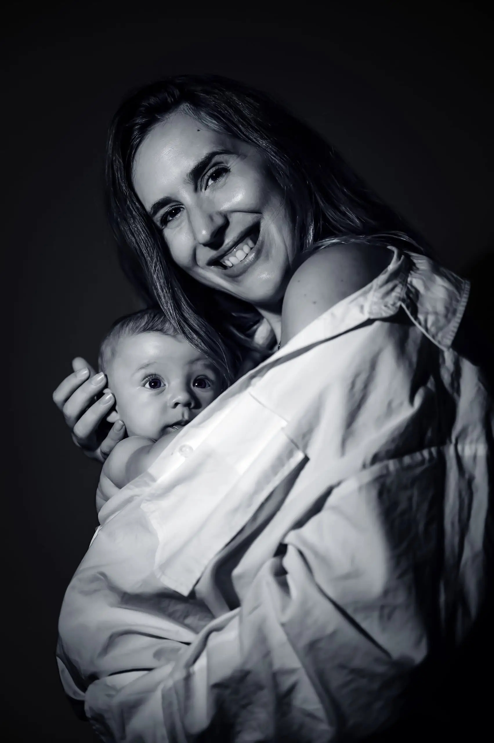 Madre abrazando a su bebé en un retrato íntimo en blanco y negro.
