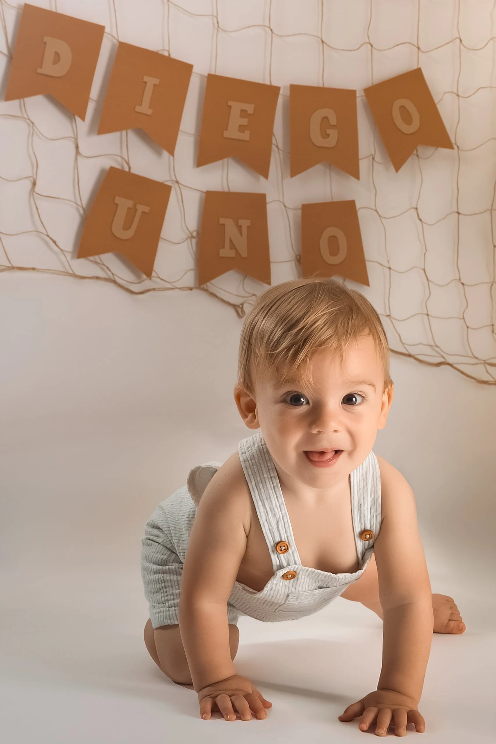 Bebé sonriente junto a la decoración de su primer cumpleaños.