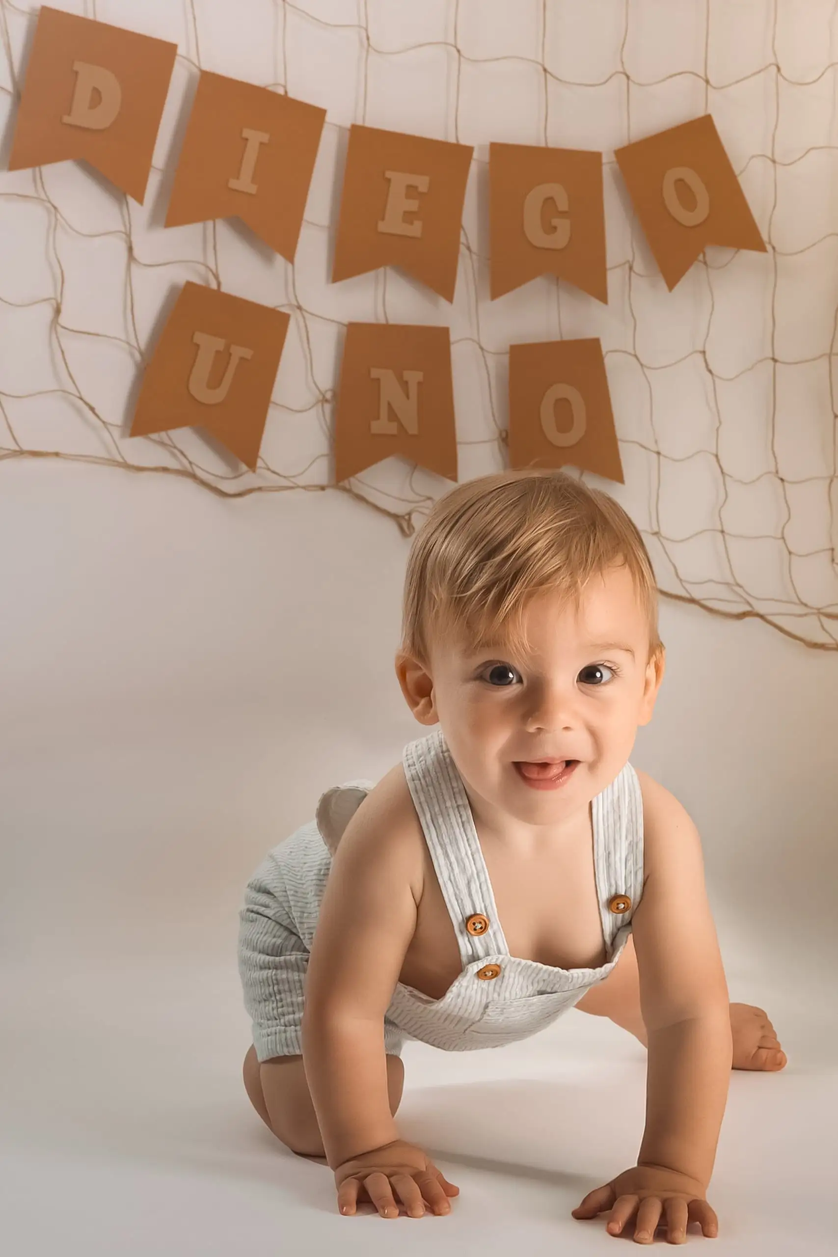 Bebé sonriente junto a la decoración de su primer cumpleaños.