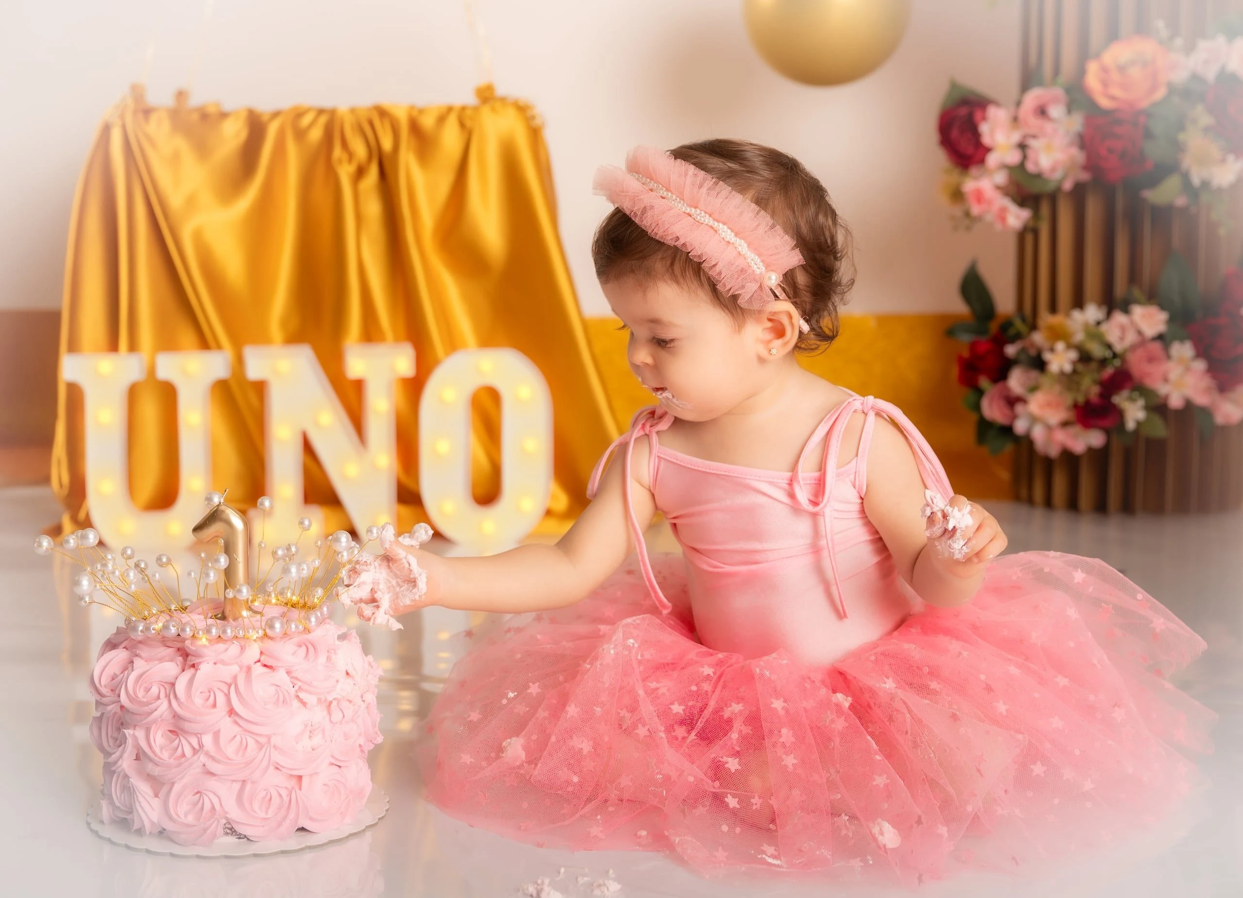 Familia acompaña a su bebé durante una sesión de primer cumpleaños.