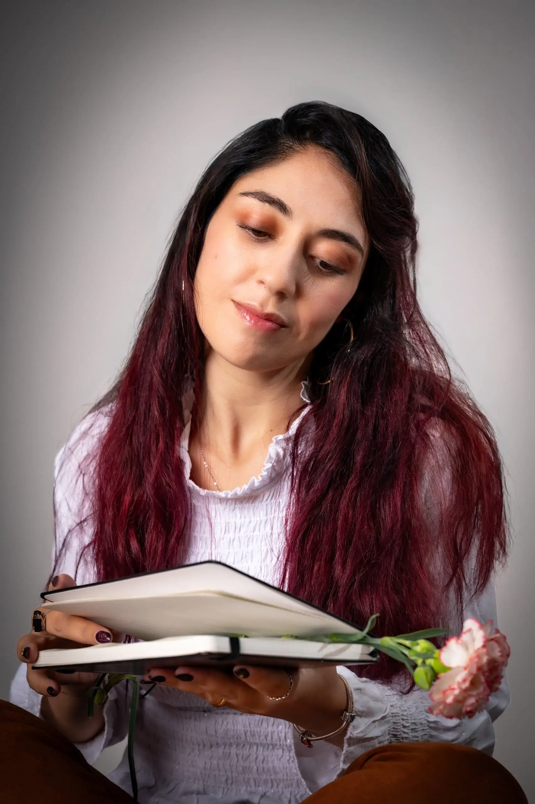 Mujer escribiendo en un cuaderno durante un retrato de estudio.