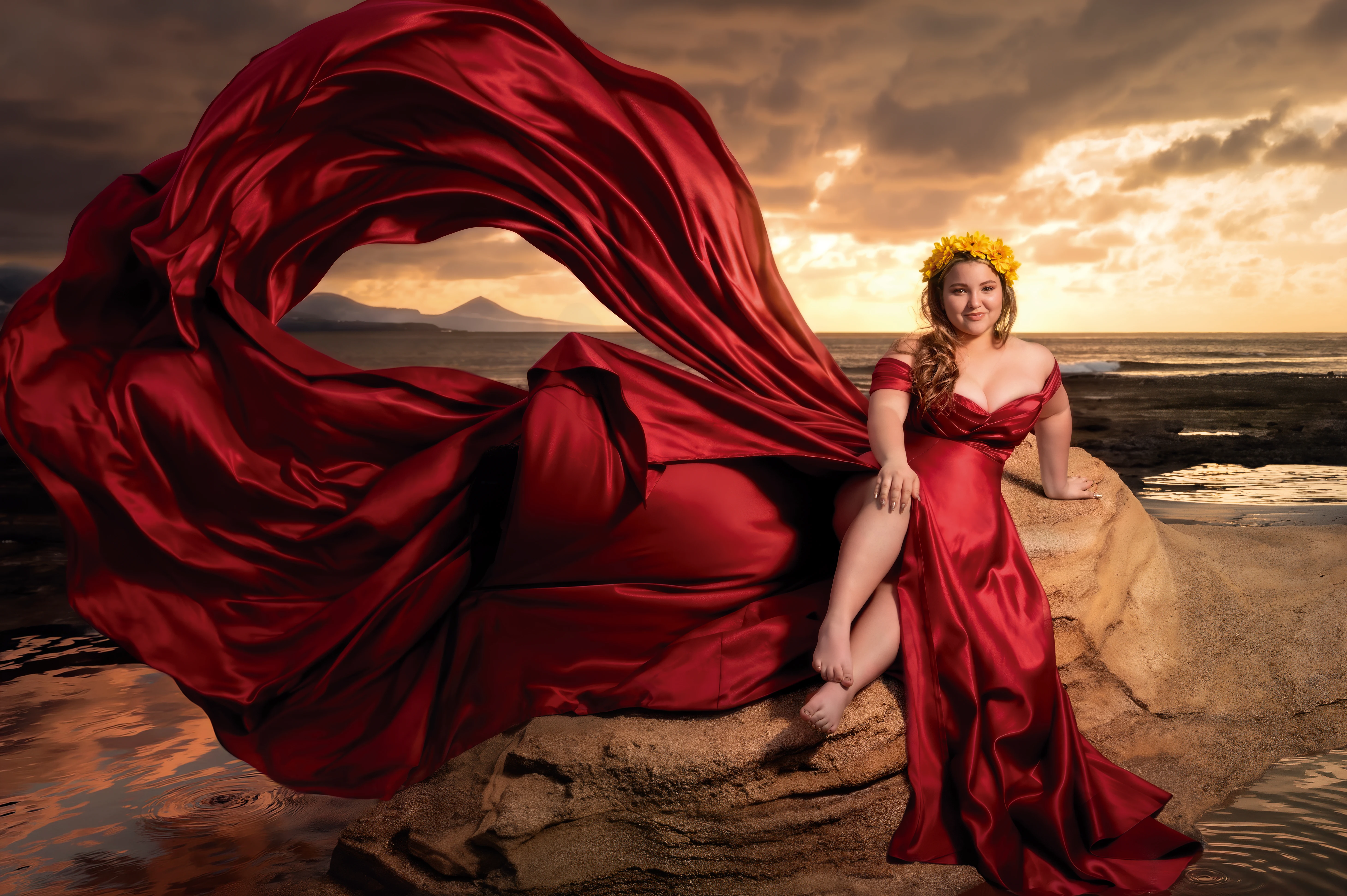 Quinceañera con vestido rojo sentada junto al mar al atardecer.
