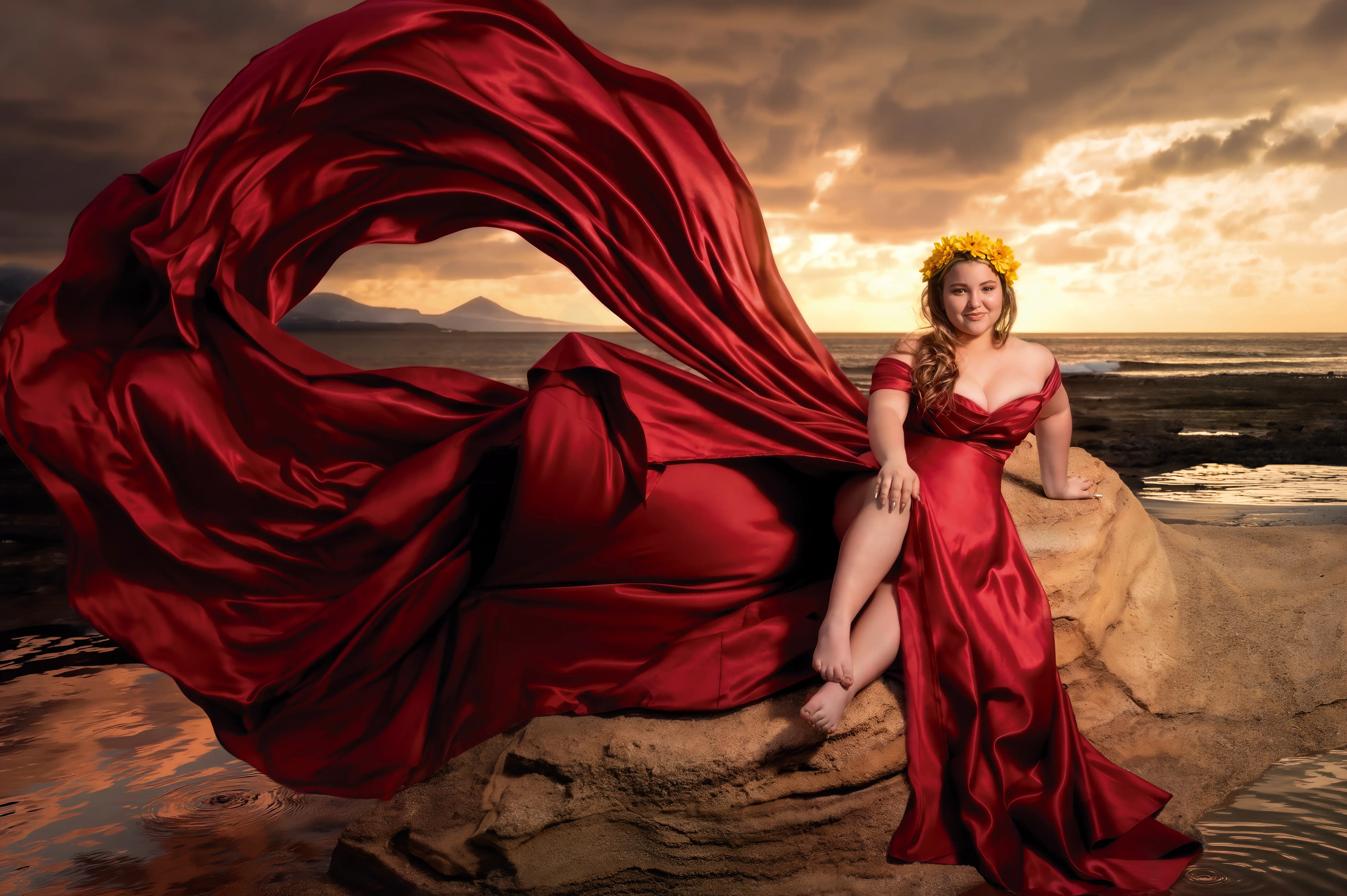 Quinceañera con vestido rojo sentada junto al mar al atardecer.
