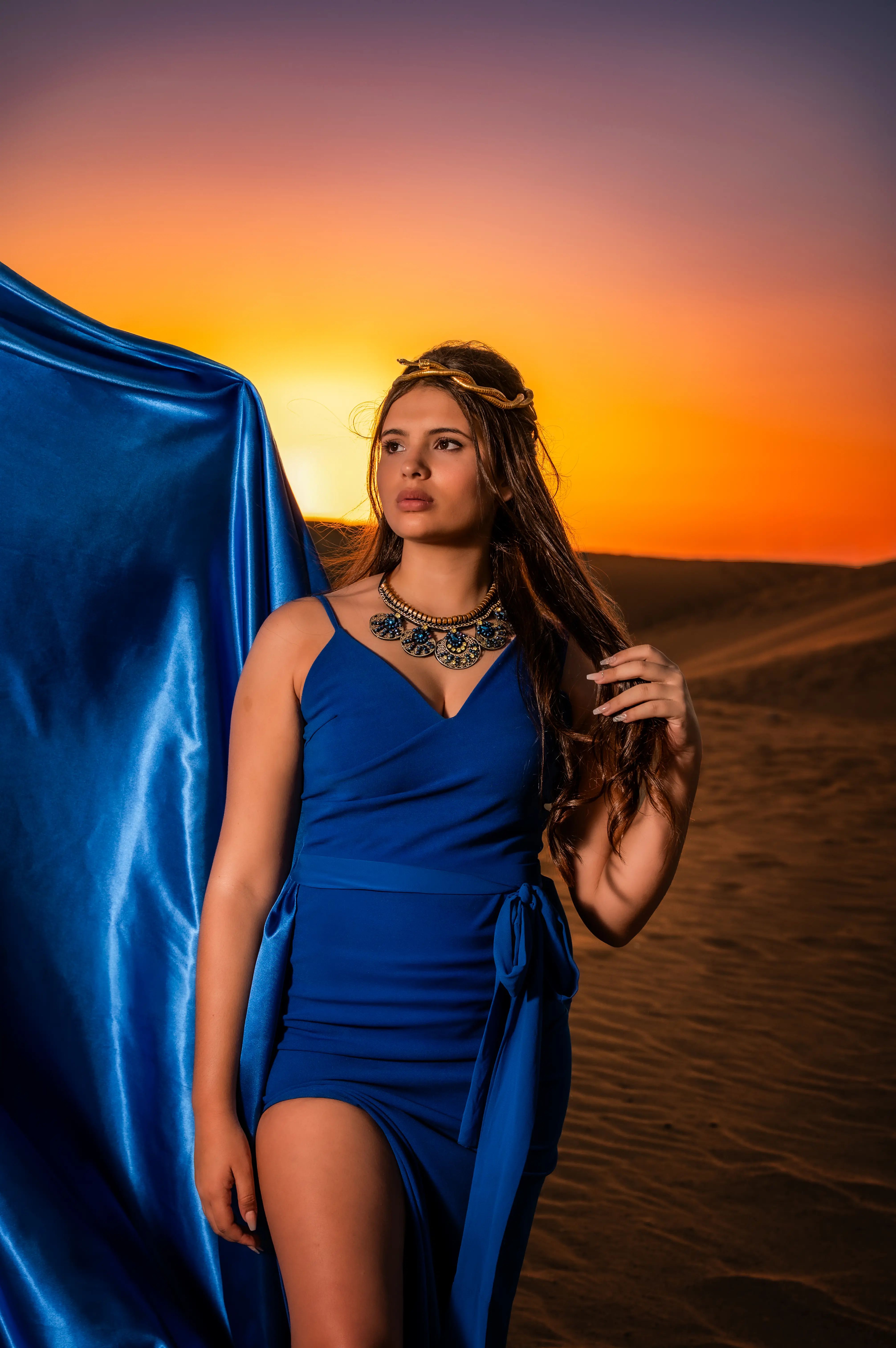 Retrato de quinceañera con vestido azul en las dunas al atardecer.