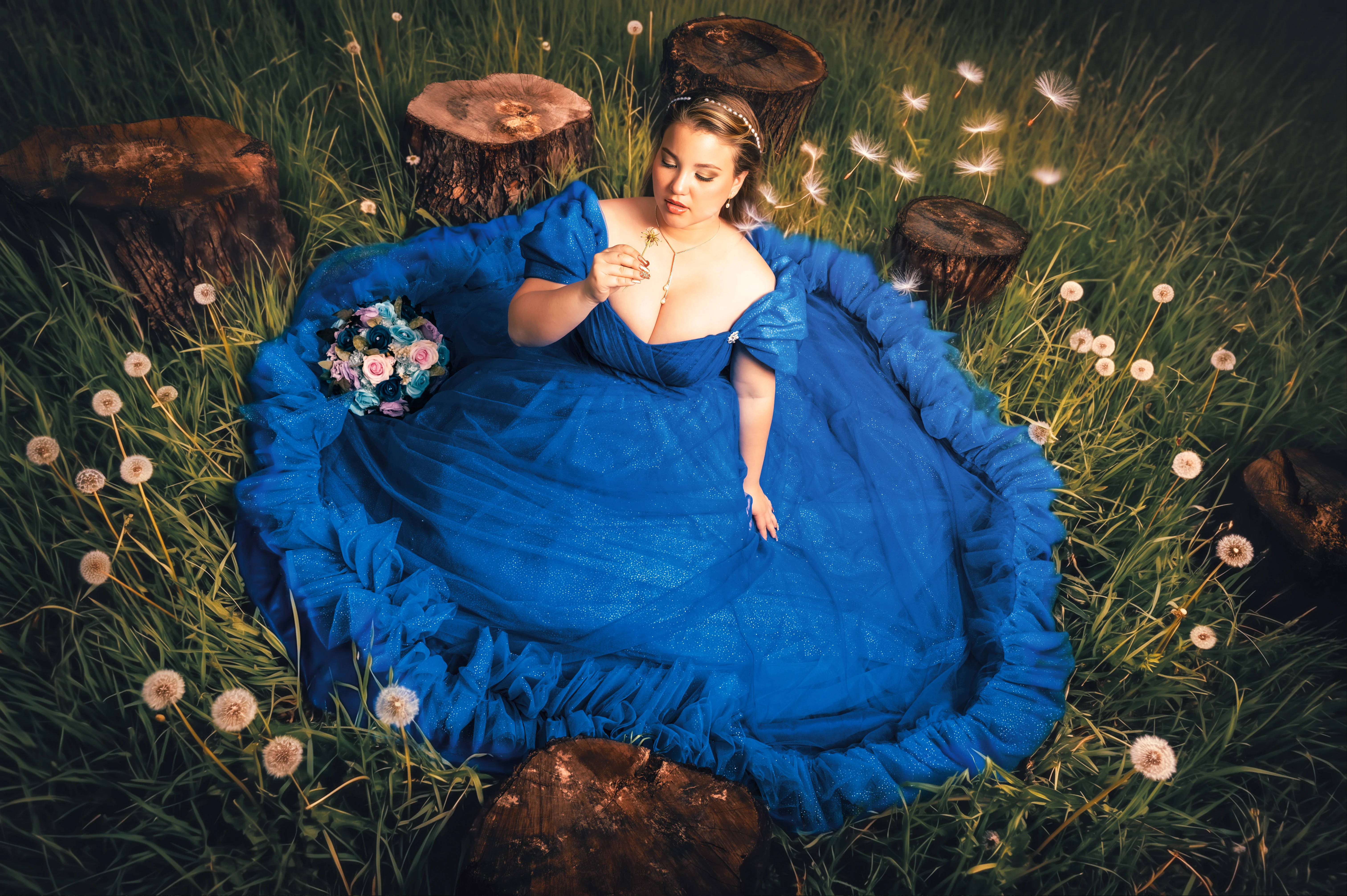 Quinceañera con vestido azul tumbada en un prado al aire libre.