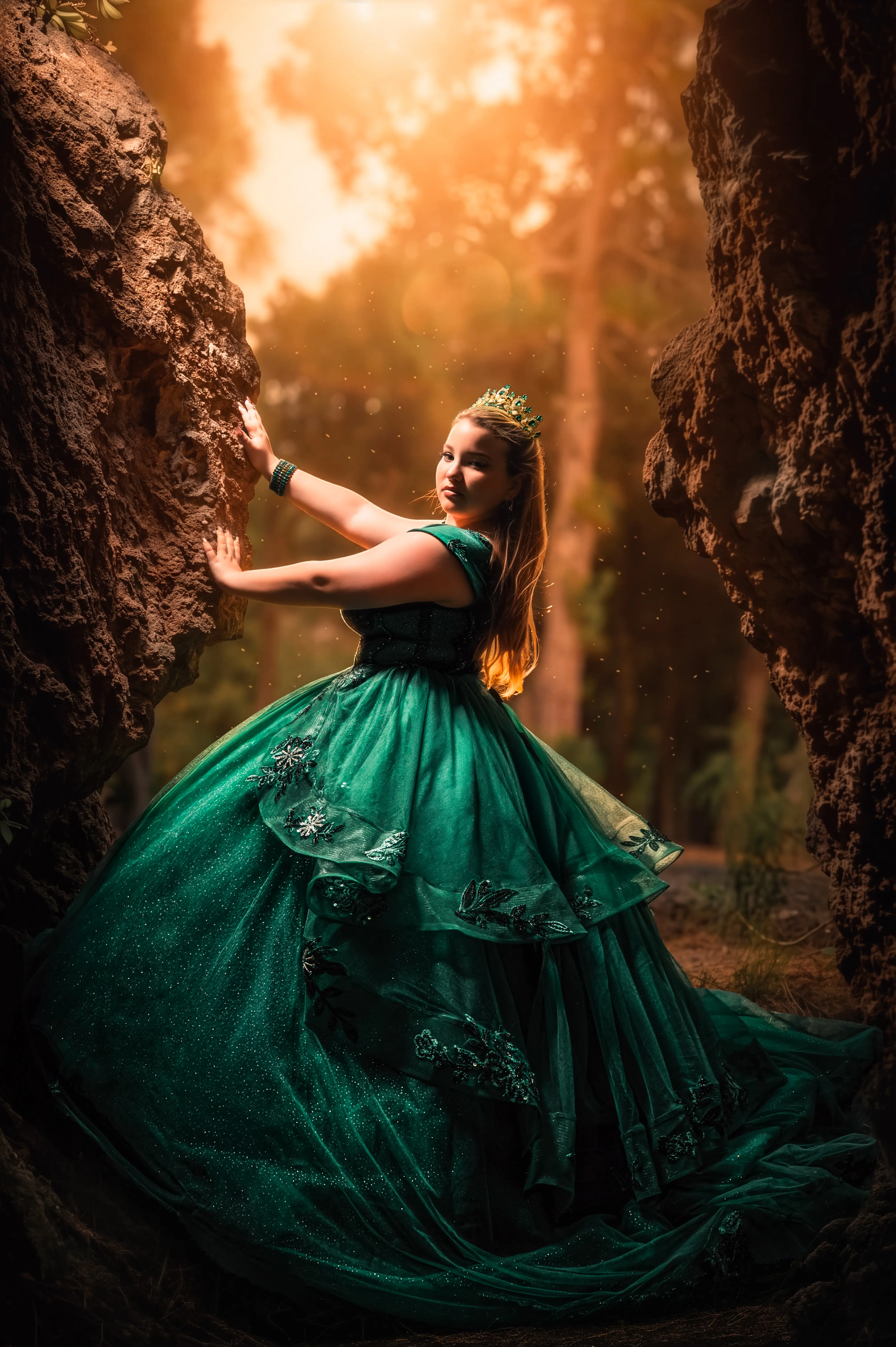 Quinceañera con vestido verde entre formaciones rocosas del bosque.