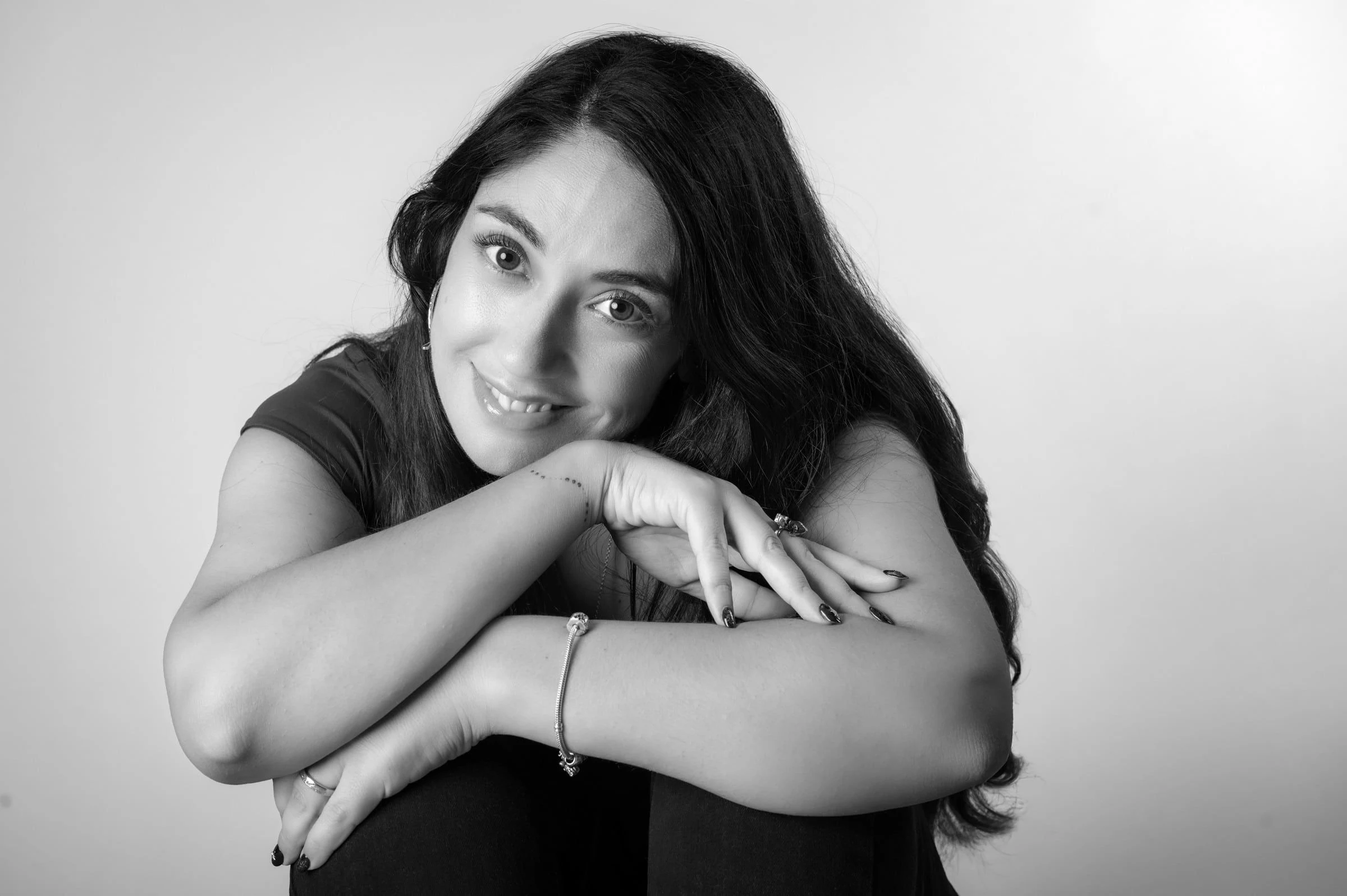 Retrato en blanco y negro de una mujer con la barbilla apoyada sobre los brazos.