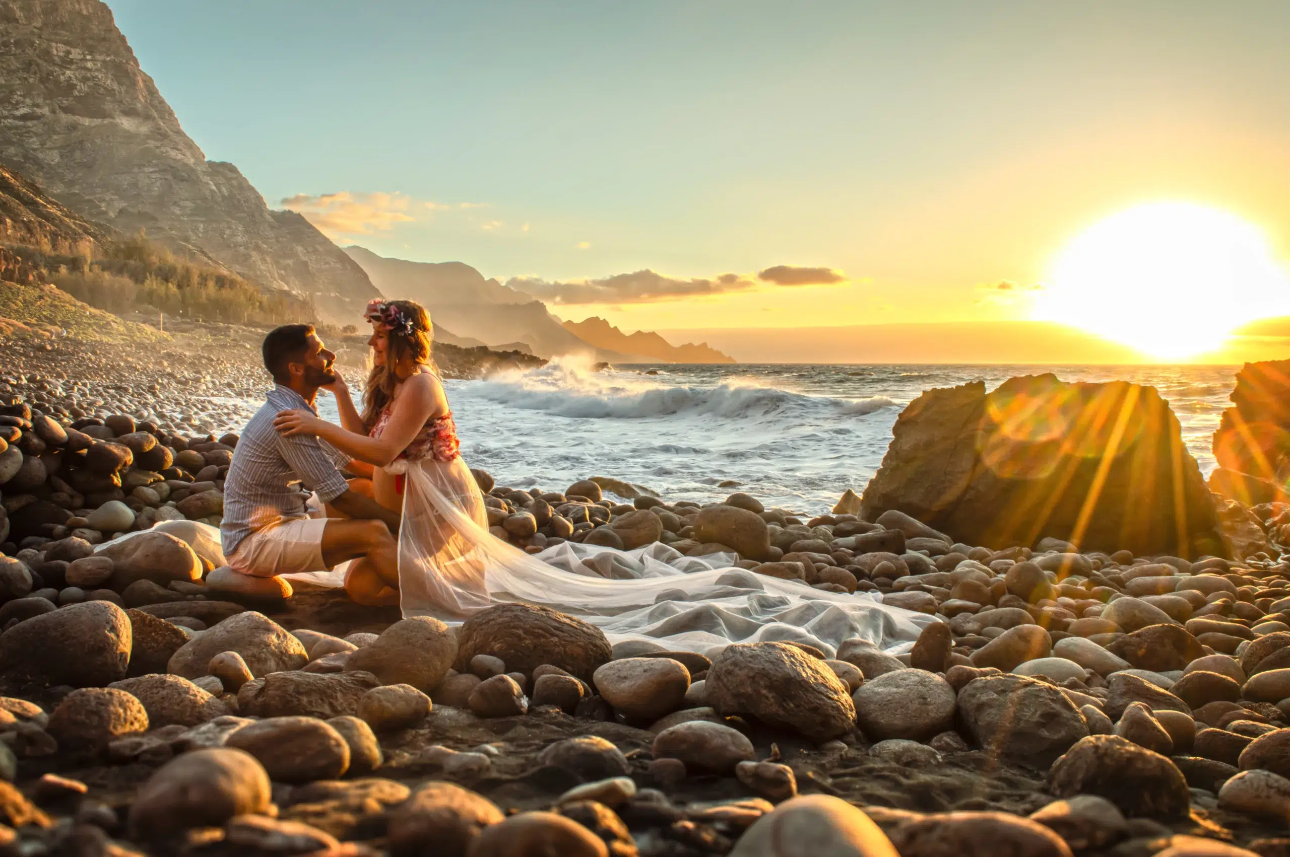 Pareja durante una sesión fotográfica de embarazo en una playa de Gran Canaria al atardecer.