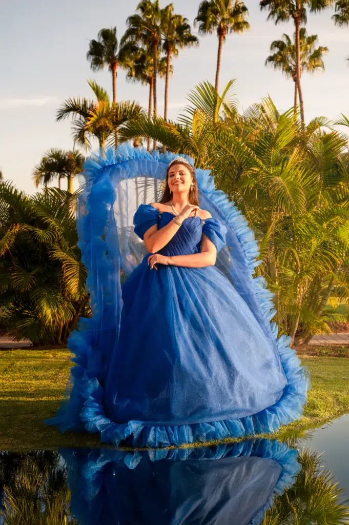 Quinceañera con corona y vestido azul posando en un jardín con palmeras durante una sesión fotográfica en Gran Canaria