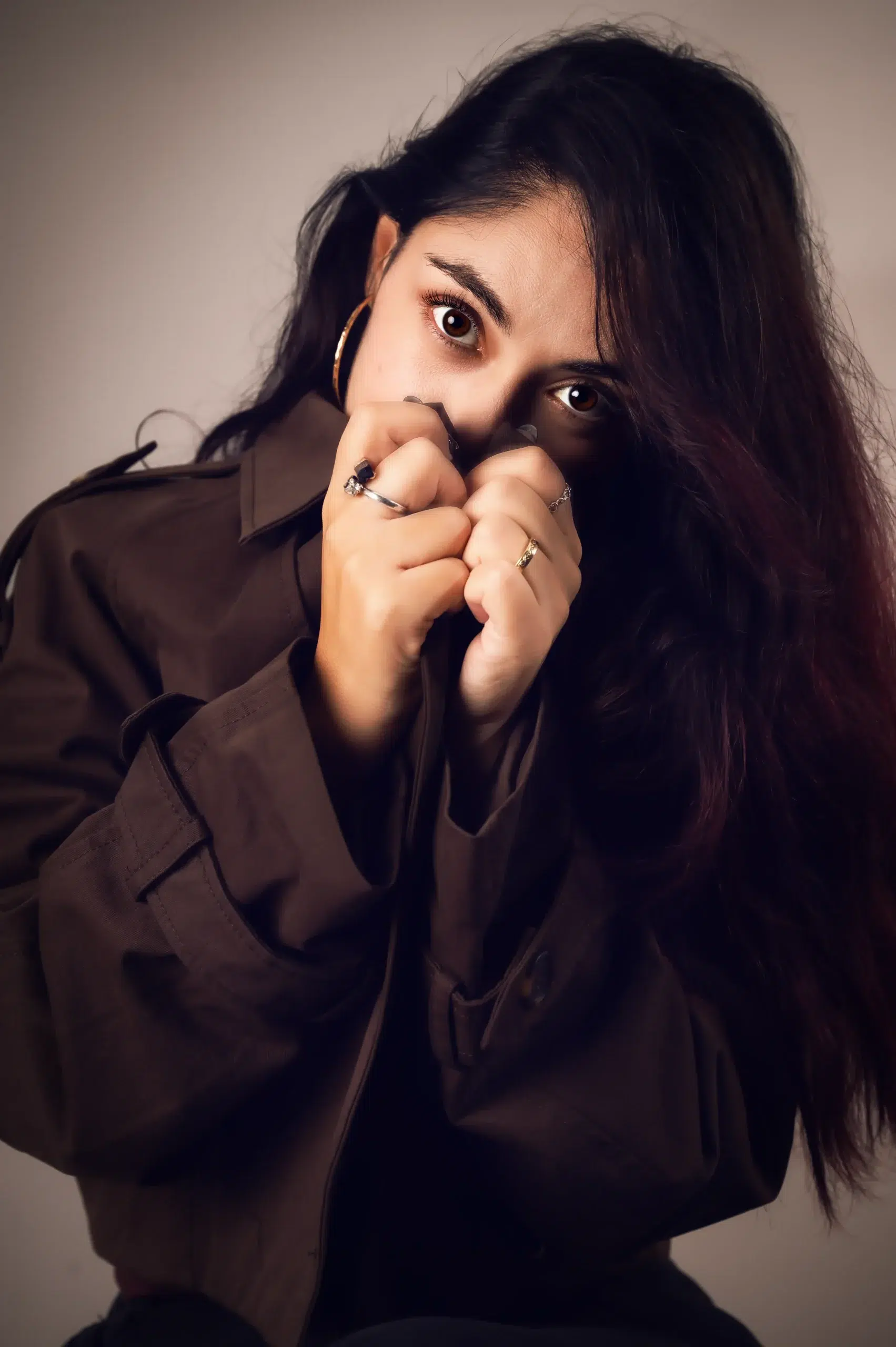 Retrato de una mujer de cabello oscuro posando con una chaqueta marrón durante una sesión fotográfica en estudio