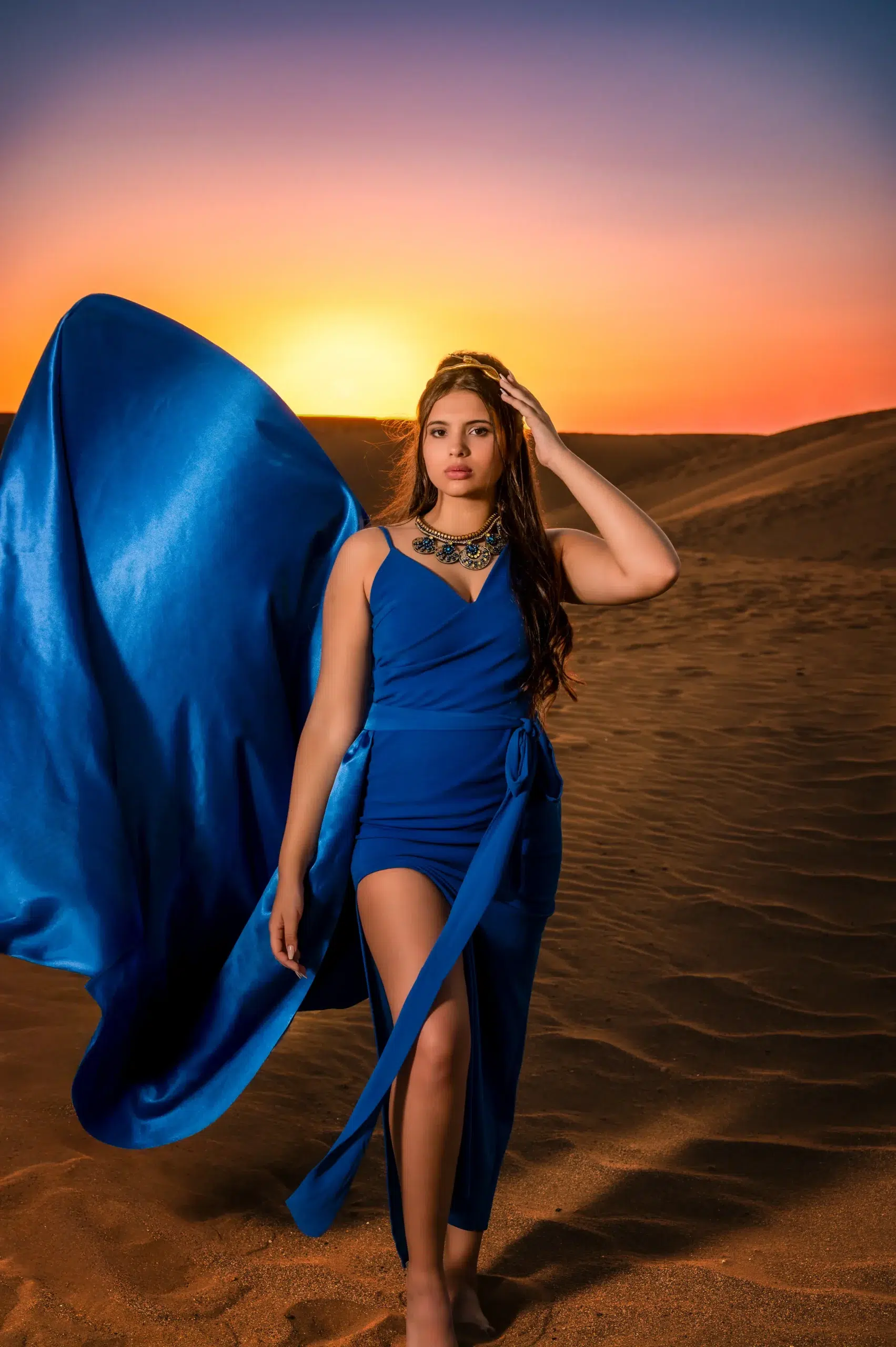 Joven con vestido azul y tela al viento durante una sesión fotográfica de quince años en Gran Canaria