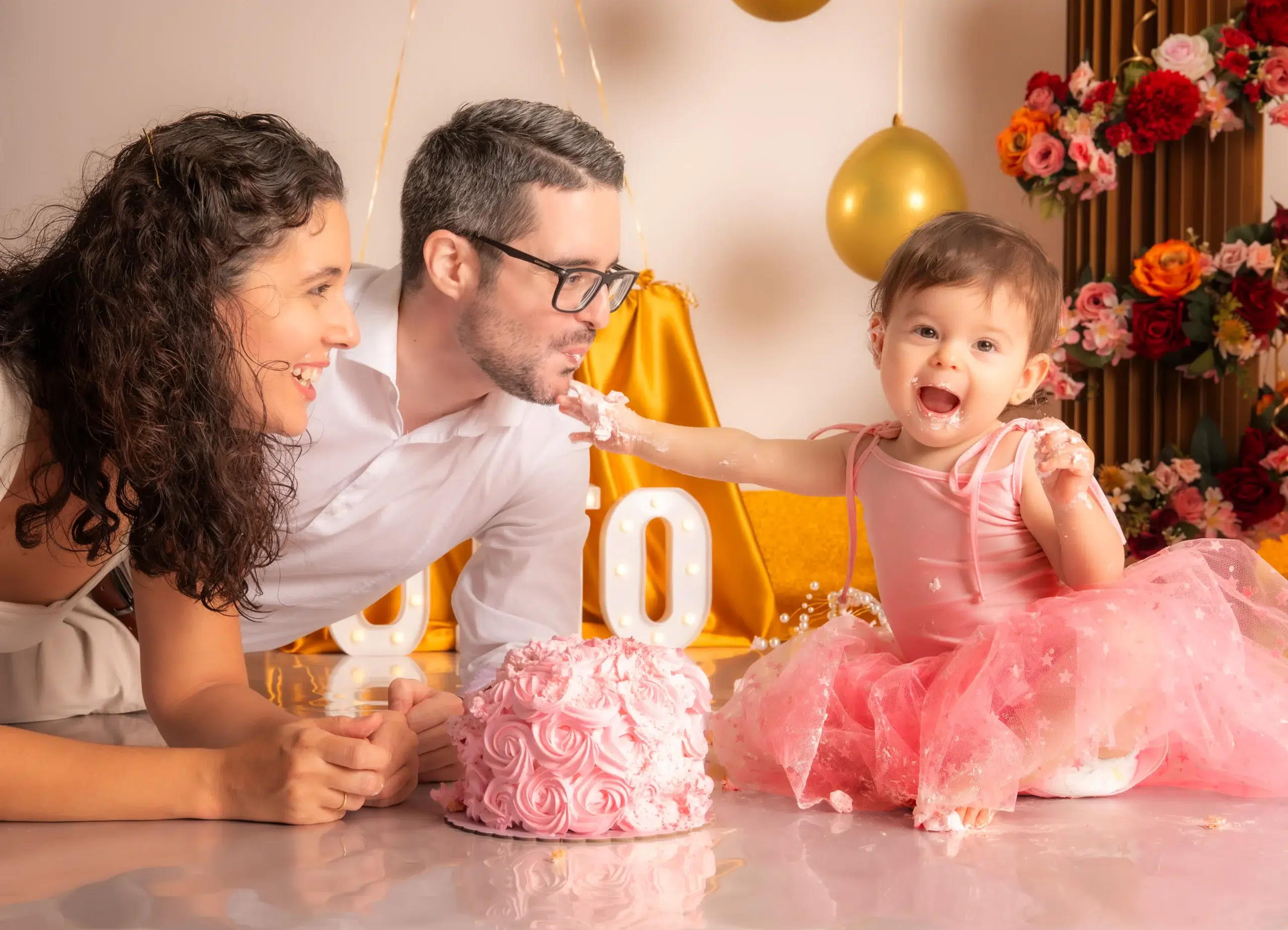 Niña ofreciendo crema de su tarta a su padre durante una sesión Smash Cake familiar de primer cumpleaños en Las Palmas