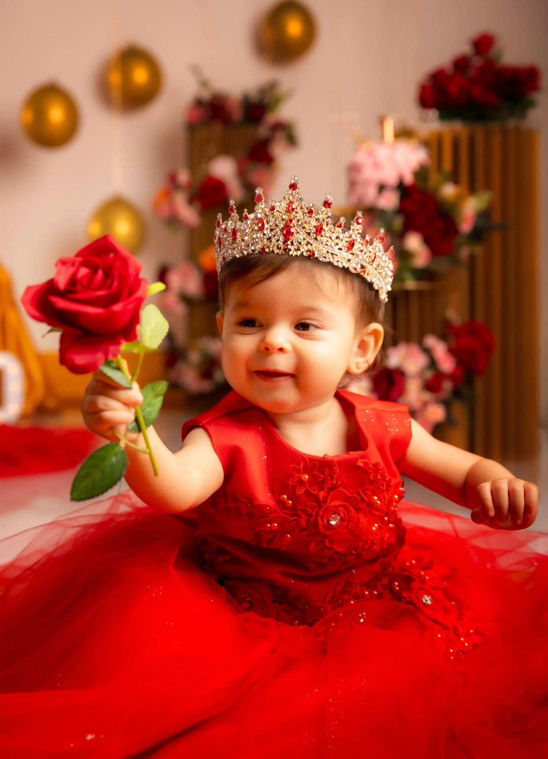 Niña con corona y vestido rojo sosteniendo una rosa durante una sesión Smash Cake de primer cumpleaños en Gran Canaria
