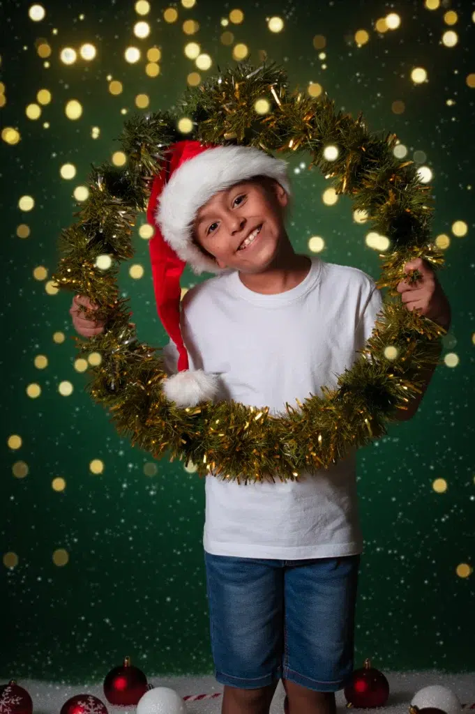 Niño sonriente enmarcado por una corona de luces navideñas.