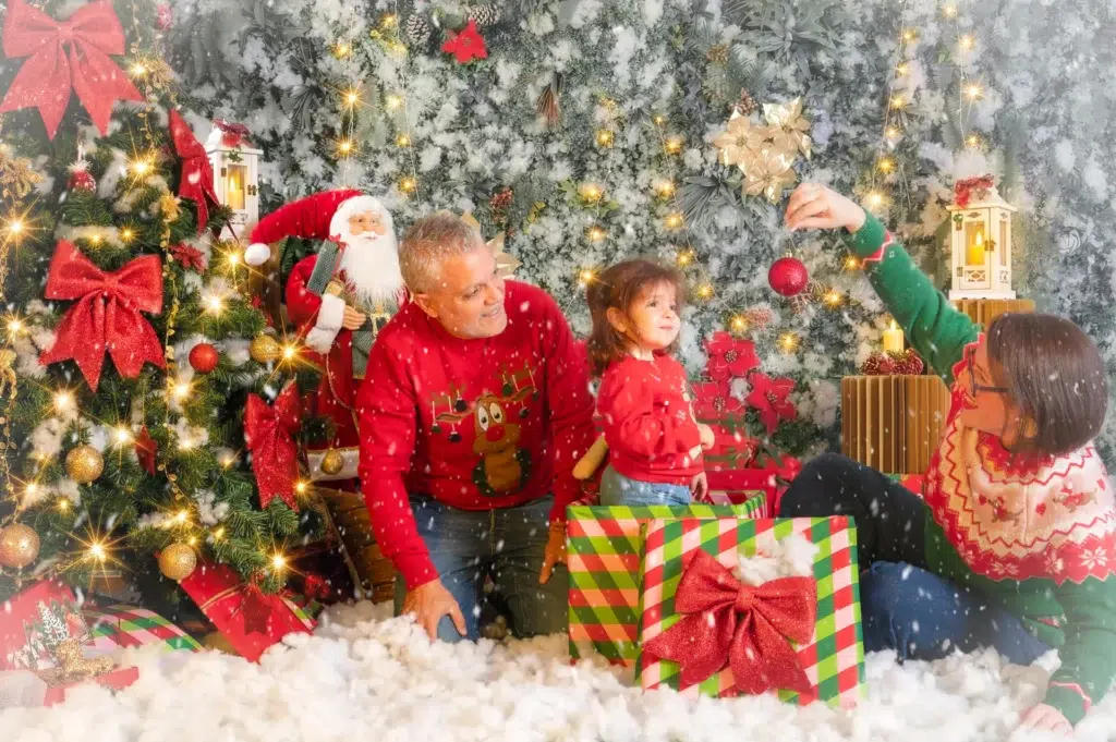 Familia jugando con adornos durante una sesión fotográfica de Navidad.