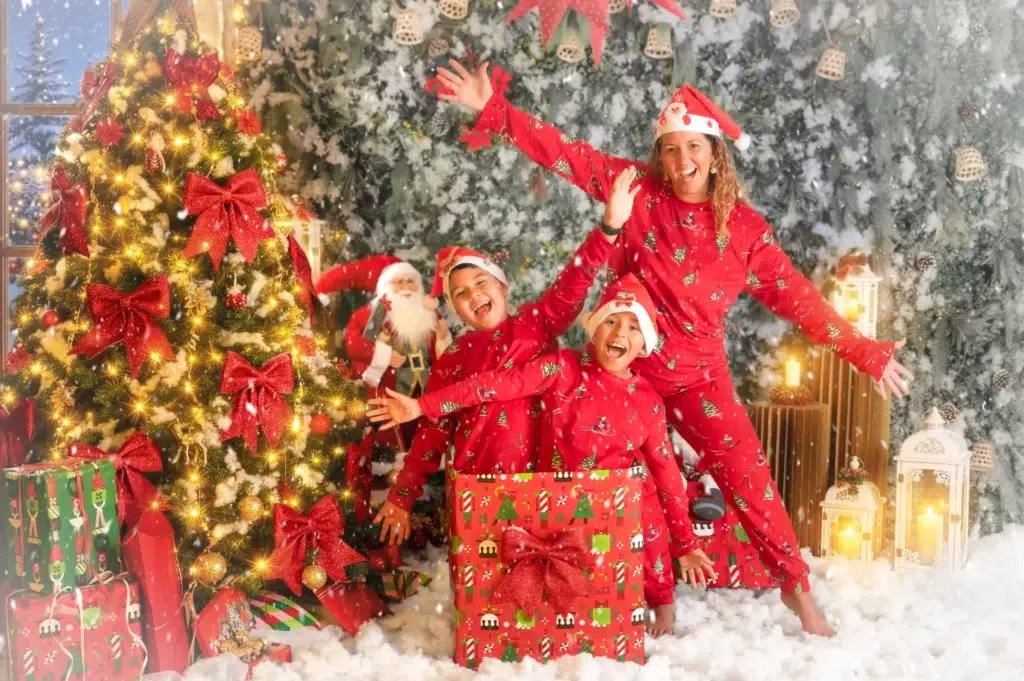 Madre y sus dos hijos con pijamas rojos en una sesión fotográfica de Navidad.